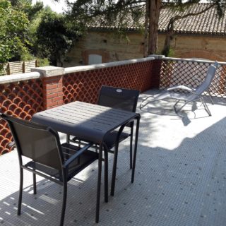 Large private terrace of suite fire with garden table and deck chairs, view on the park and swimming pool