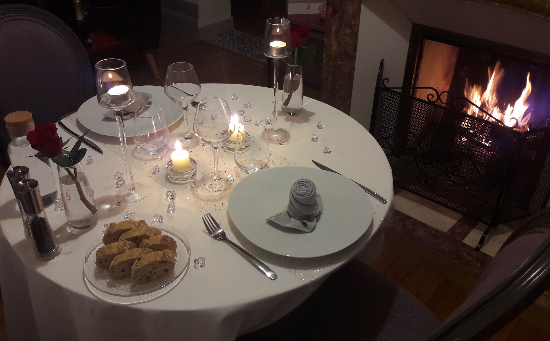 Elegant table with quality plates and glasses, romantic setting with candles and fireplace