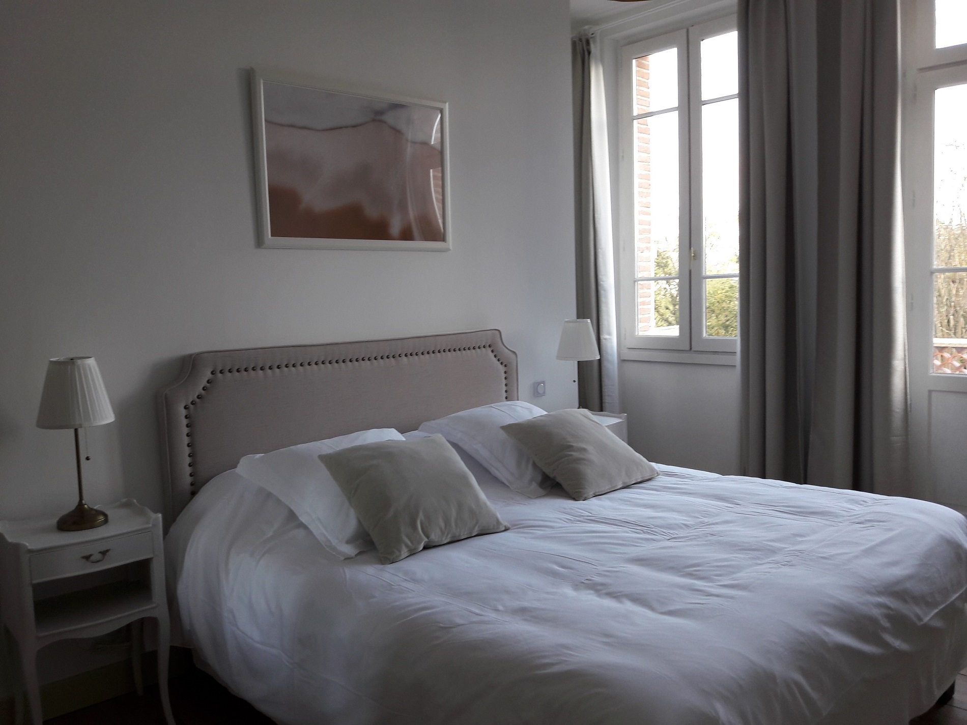 Very comfortable king size bed with fluffy pillows, nice beige bed head, large windows overlooking the garden