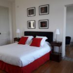 Beautiful room in shades of red with black headboard, photo frames, bedside tables and beautiful old parquet floors