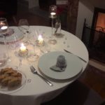 Beautiful romantic table setting with pretty plates and glasses, candles, flowers and open fire