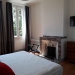 Beautiful bedroom with marble fireplace and large window with nice curtains opening onto the terrace